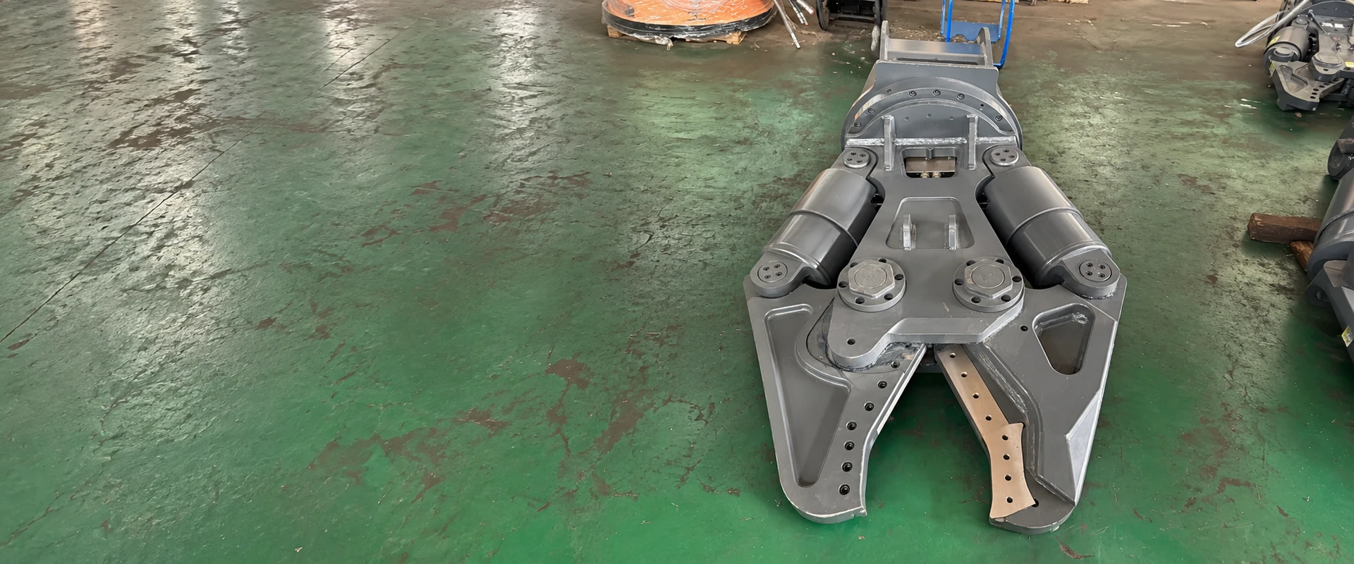 Complete grey hydraulic shear with twin cylinders and open cutting jaw in a workshop