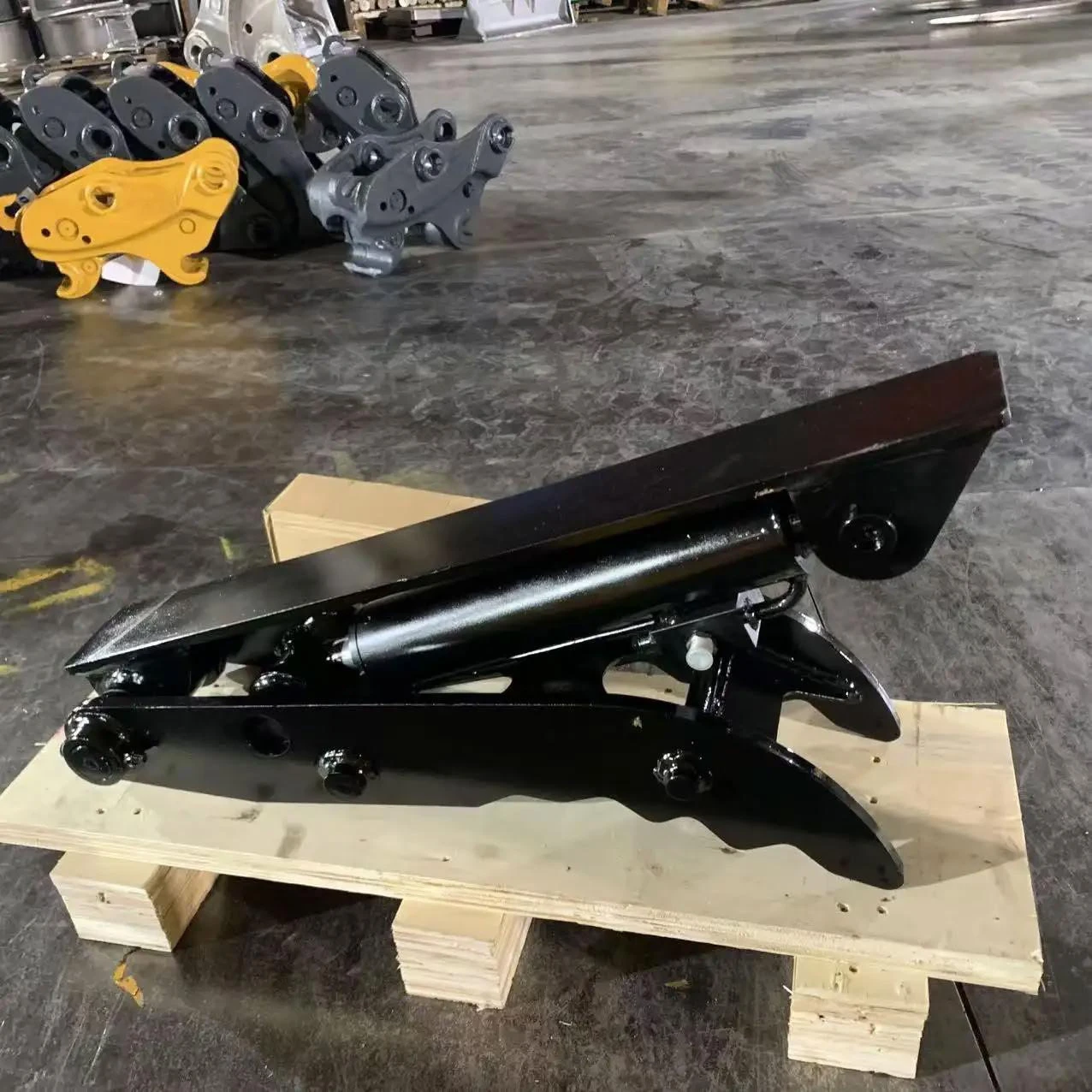 Black hydraulic thumb with cylinder and pins on a wooden pallet