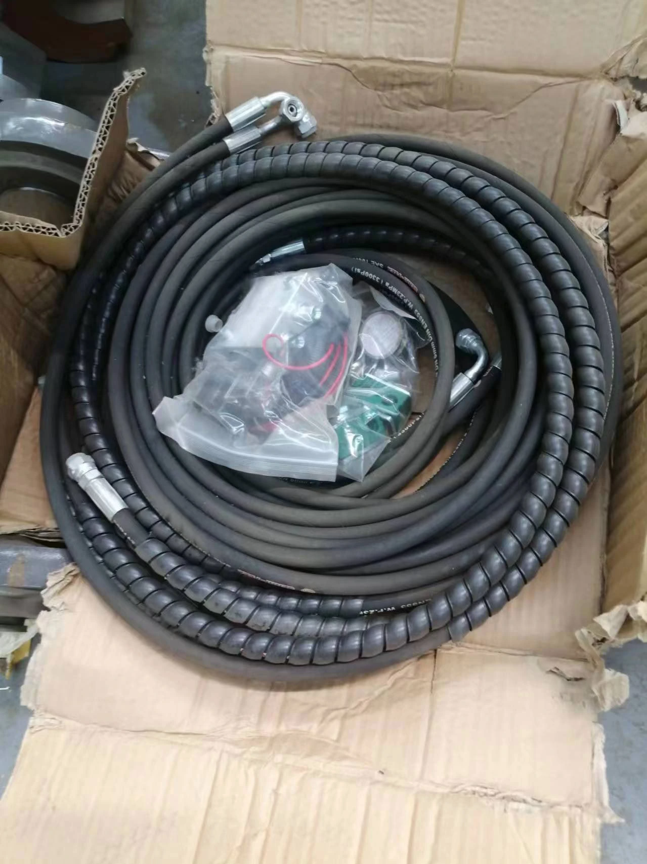 Hydraulic hoses with protective sleeves and metal fittings in a box